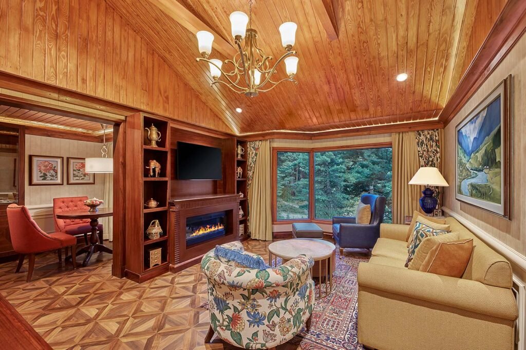 Luxury cottage living room at Welcomhotel Pine N Peak in Pahalgam overlooking Kashmir's pine forests.