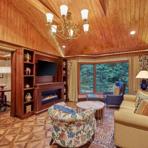Luxury cottage living room at Welcomhotel Pine N Peak in Pahalgam overlooking Kashmir's pine forests.